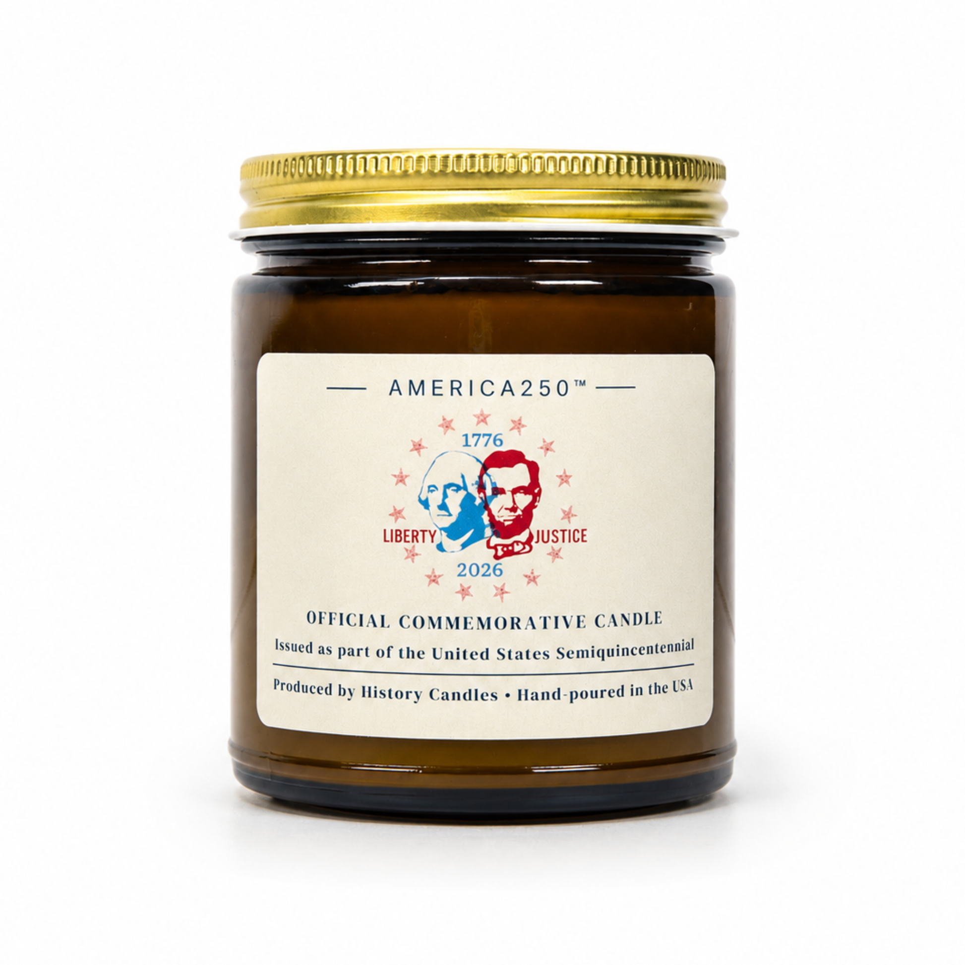 An amber glass jar candle with a gold metal lid and a cream-colored label. The label features the brand name 'AMERICA250' and a commemorative design for 'Liberty and Justice 2026' with portraits of Thomas Jefferson and Abraham Lincoln.